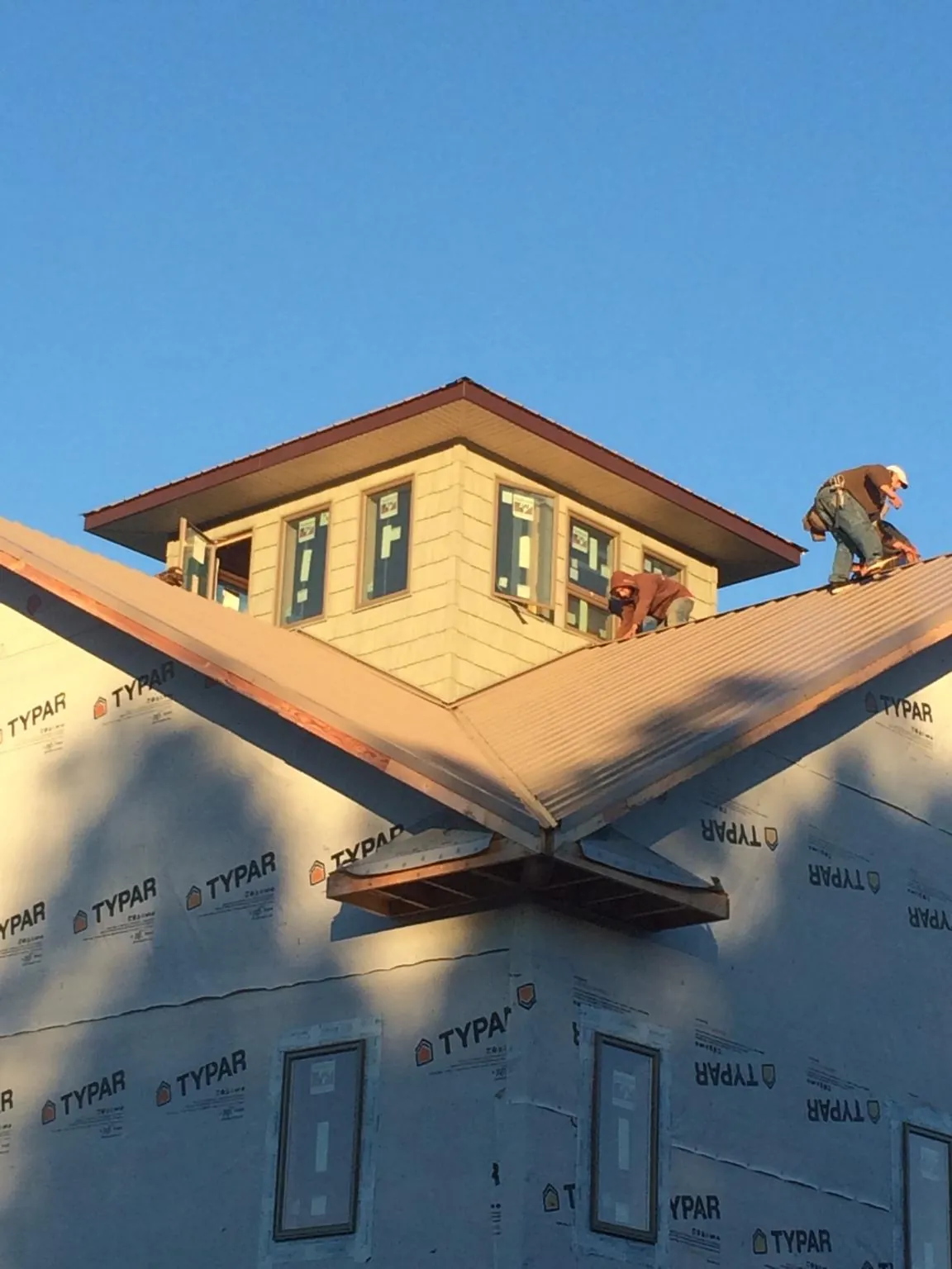 Roofers working around a rooftop cupola on a new metal roof at sunset — Roof Waterproofing in Millville by Roofing Brothers